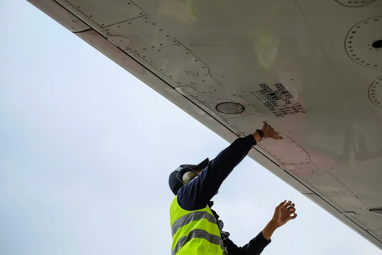 Aircraft technician in a safety vest under a plane