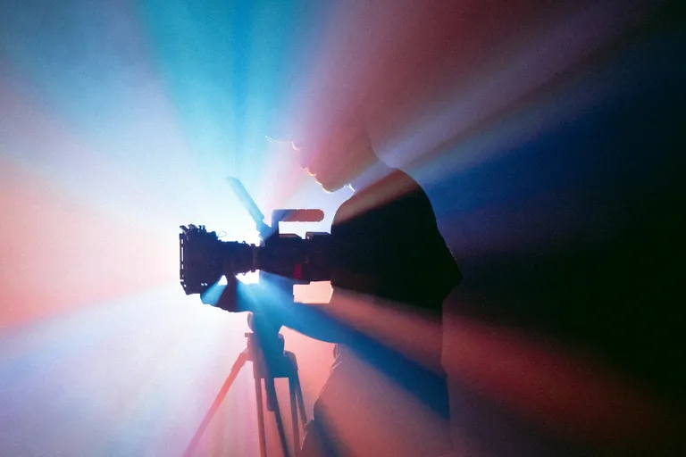 Camera operator filming on a tripod in studio lighting