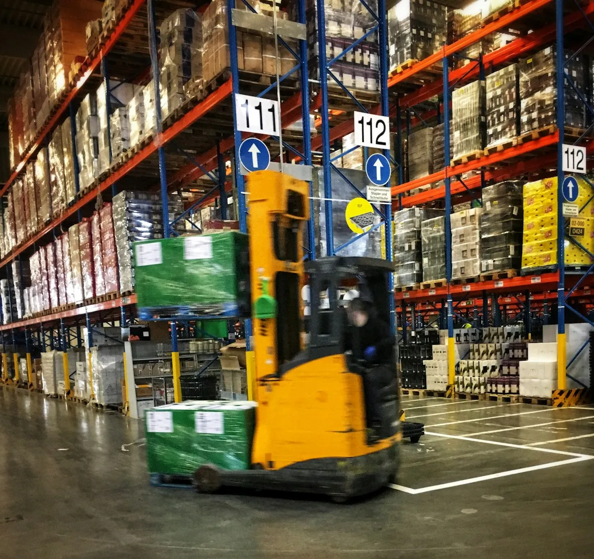 Forklift driving through a warehouse full of pallets