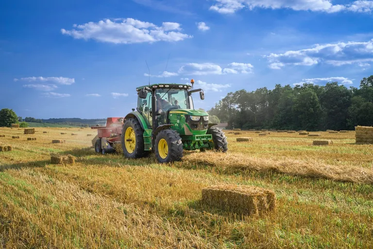 Green tractor on a grass field under a blue sky