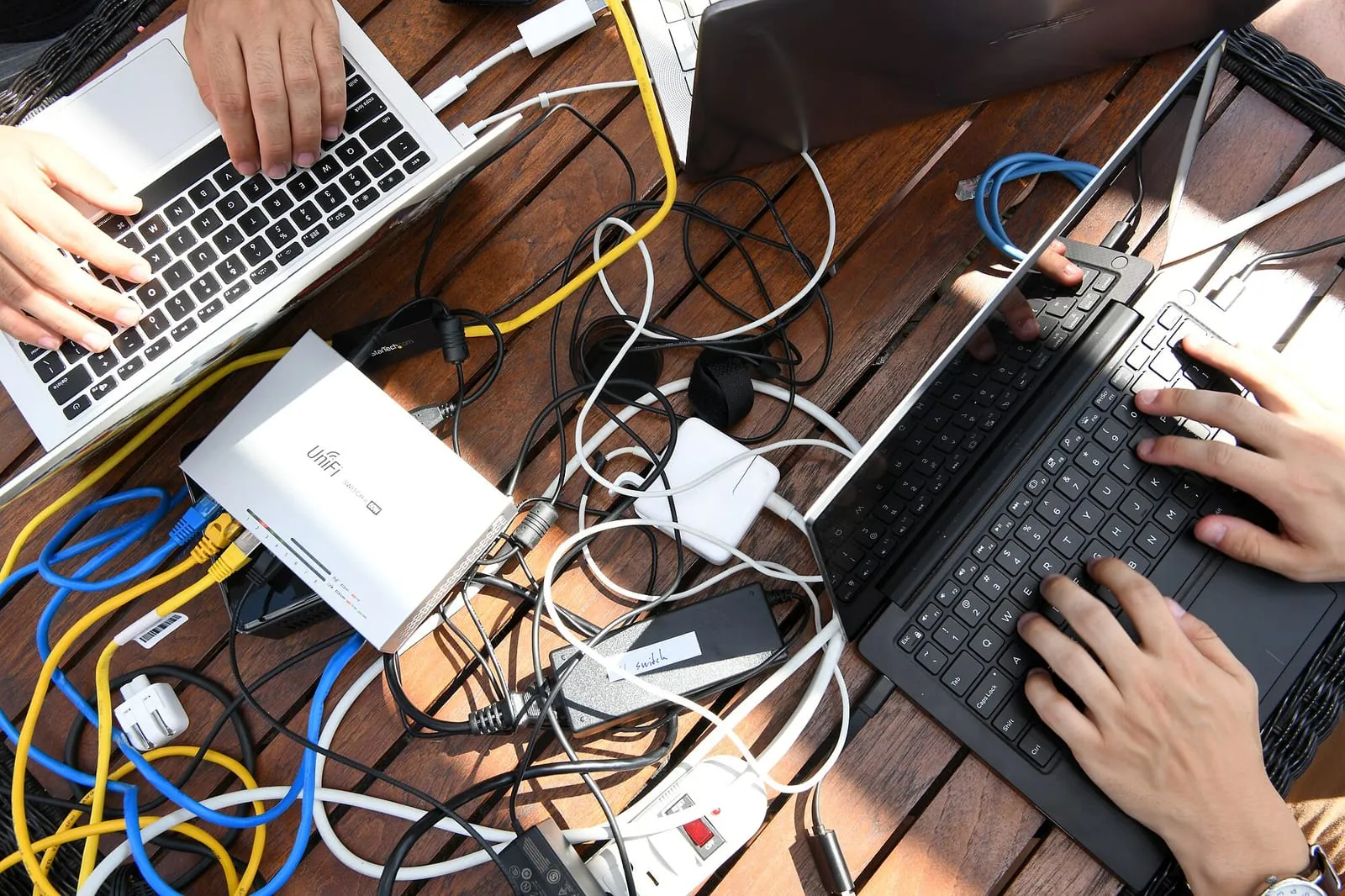 Hands on laptops and network cables at a hacking competition workstation