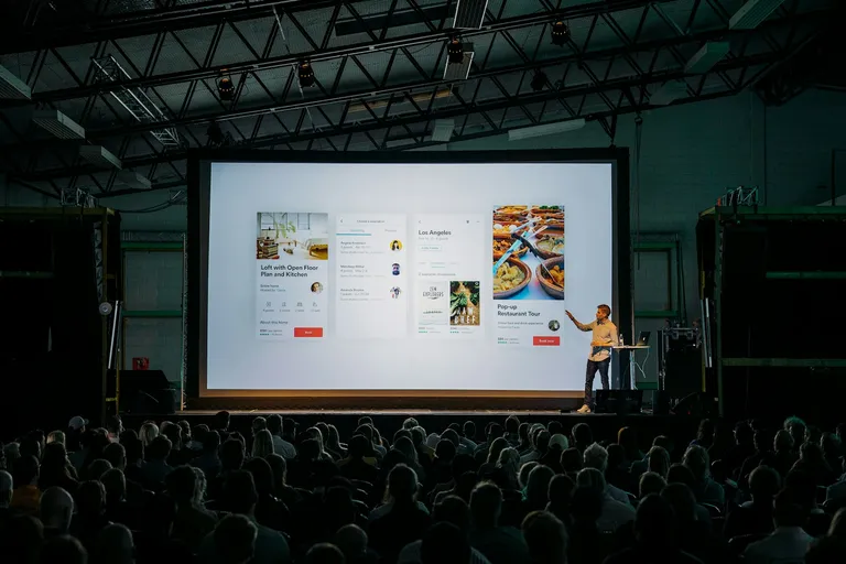 Presenter in front of a large screen at a conference