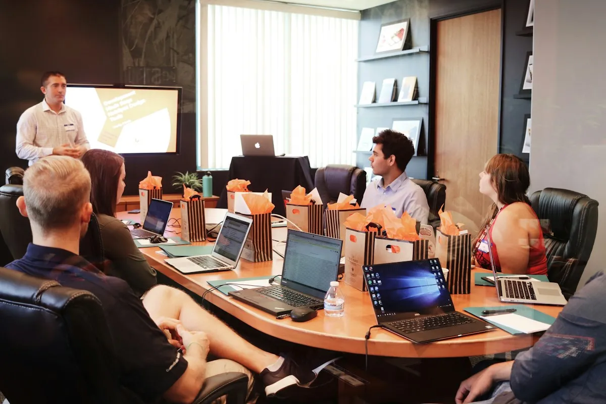 Presenter leading a meeting with laptops on the table