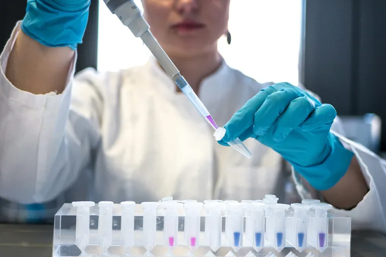 Scientist using a pipette with test tubes in a lab