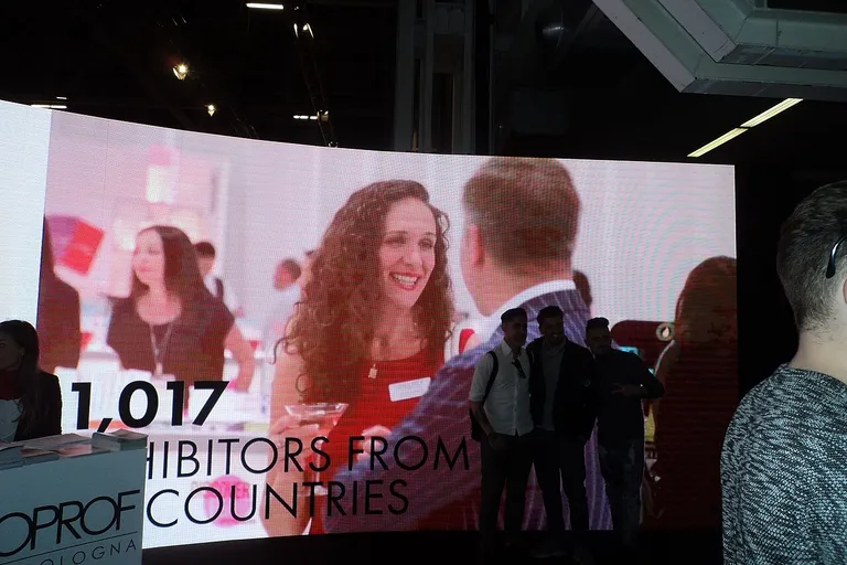Visitors talking to exhibitors at a professional beauty trade fair stand