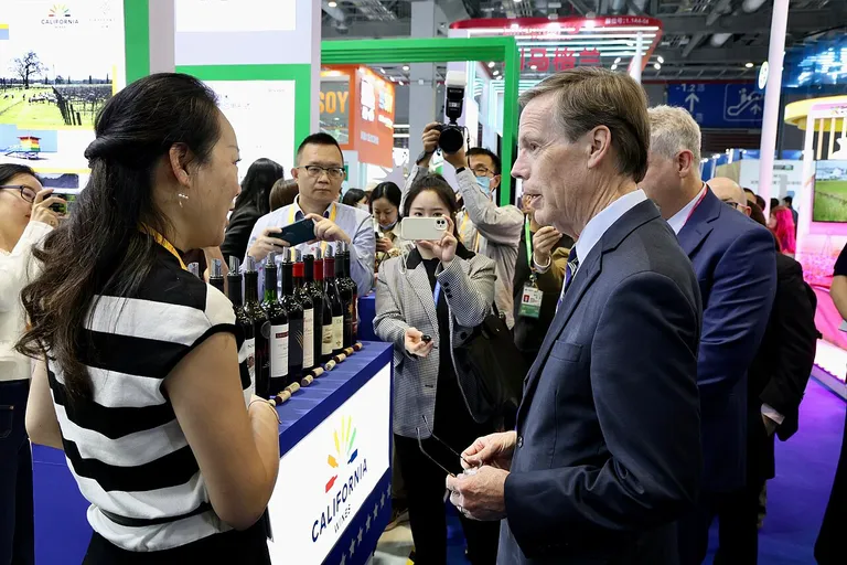 Visitors tasting imported wine at a foreign exhibitor's booth at the China International Import Expo