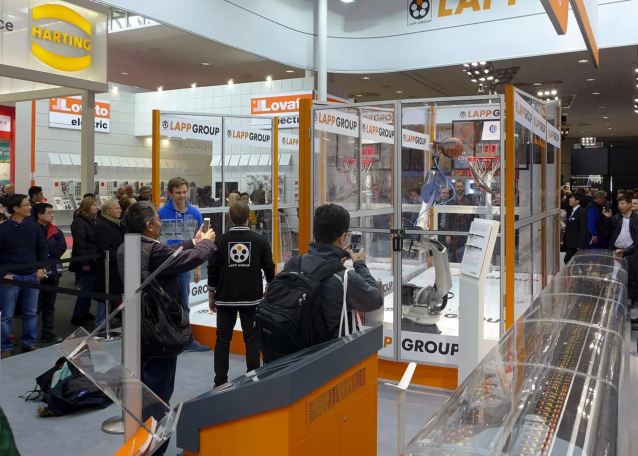 Visitors walking between exhibitor stands at a large industrial trade fair