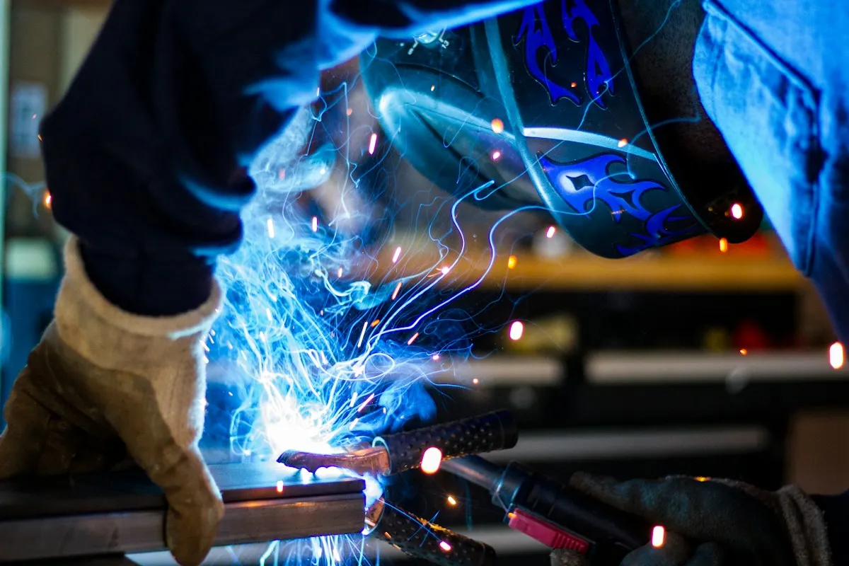 Welder in a protective helmet working on metal with sparks