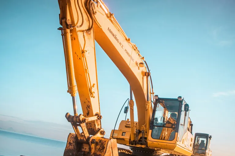 Yellow excavator on rocky ground near water